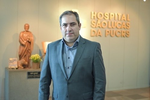 Dr. Fabiano Ramos no hall do hospital, em frente ao logo da instituição